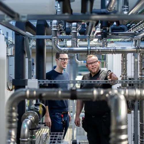 Zwei Techniker stehen vor einer Kälteanlage. 
