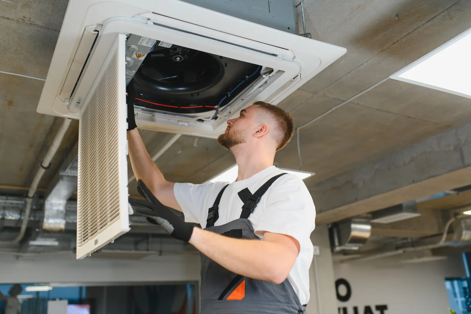 Ein Techniker installiert eine Klimaanlage an der Decke.