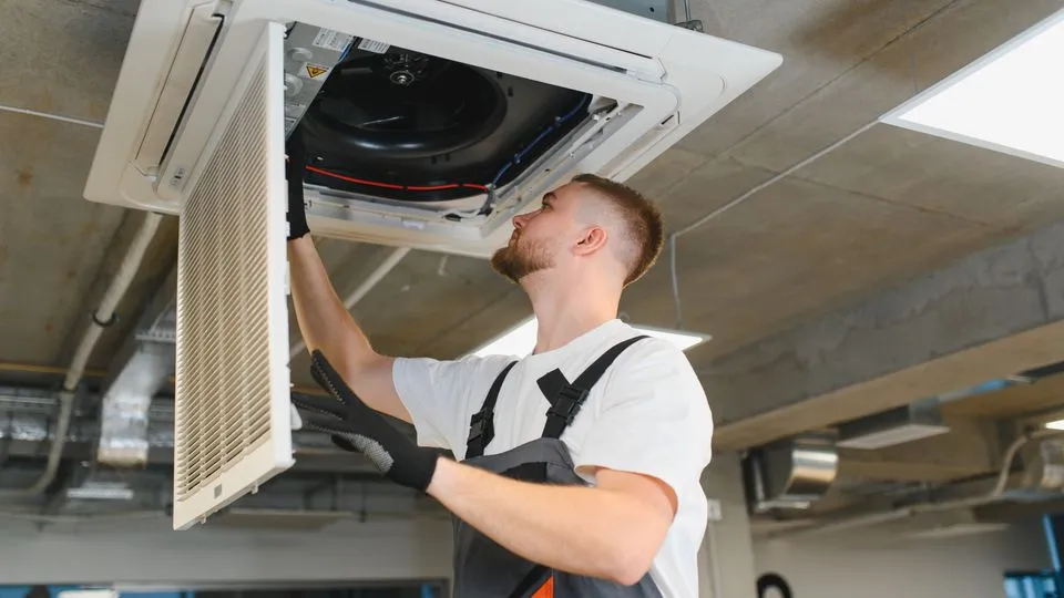 Ein Techniker installiert eine Klimaanlage an der Decke.