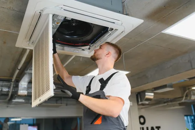 Ein Techniker installiert eine Klimaanlage an der Decke.