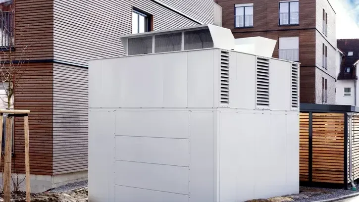 Die vier Luft/Wasser-Wärmepumpen stehen in einer Sicht- und Schallschutzeinhausung im Außenbereich an den Stirnseiten der Wohnblocks.