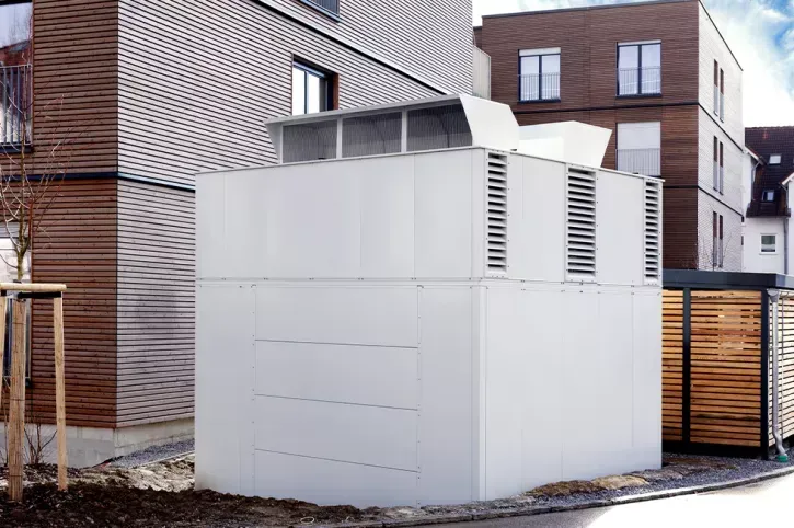 Die vier Luft/Wasser-Wärmepumpen stehen in einer Sicht- und Schallschutzeinhausung im Außenbereich an den Stirnseiten der Wohnblocks.