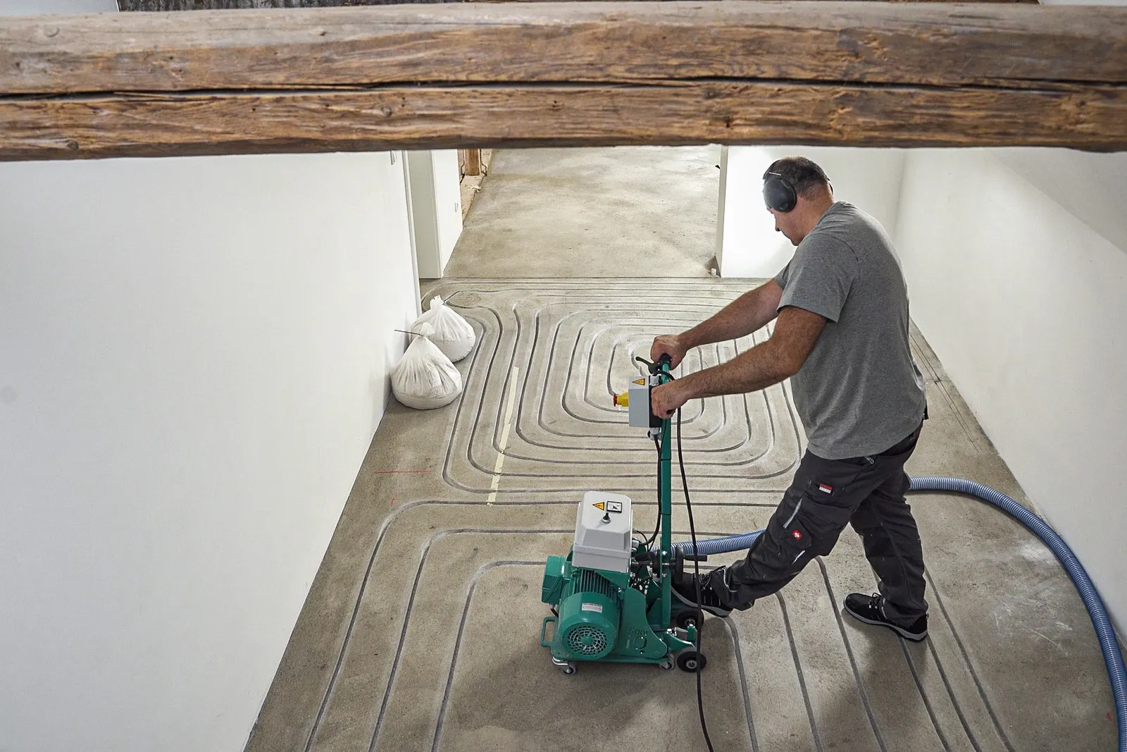 Ein Handwerker fräst die Leitungen für eine Fußbodenheizung. 