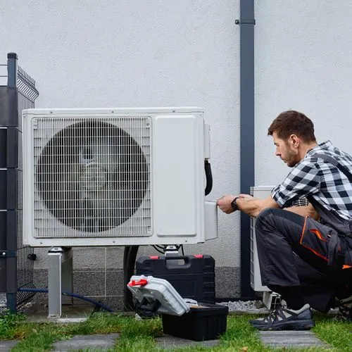 Ein Techniker installiert eine Wärmepumpe vor einem Wohnhaus.