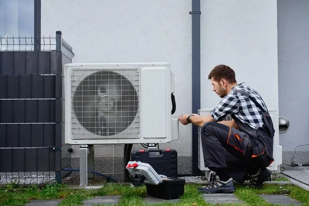 Ein Techniker installiert eine Wärmepumpe vor einem Wohnhaus.